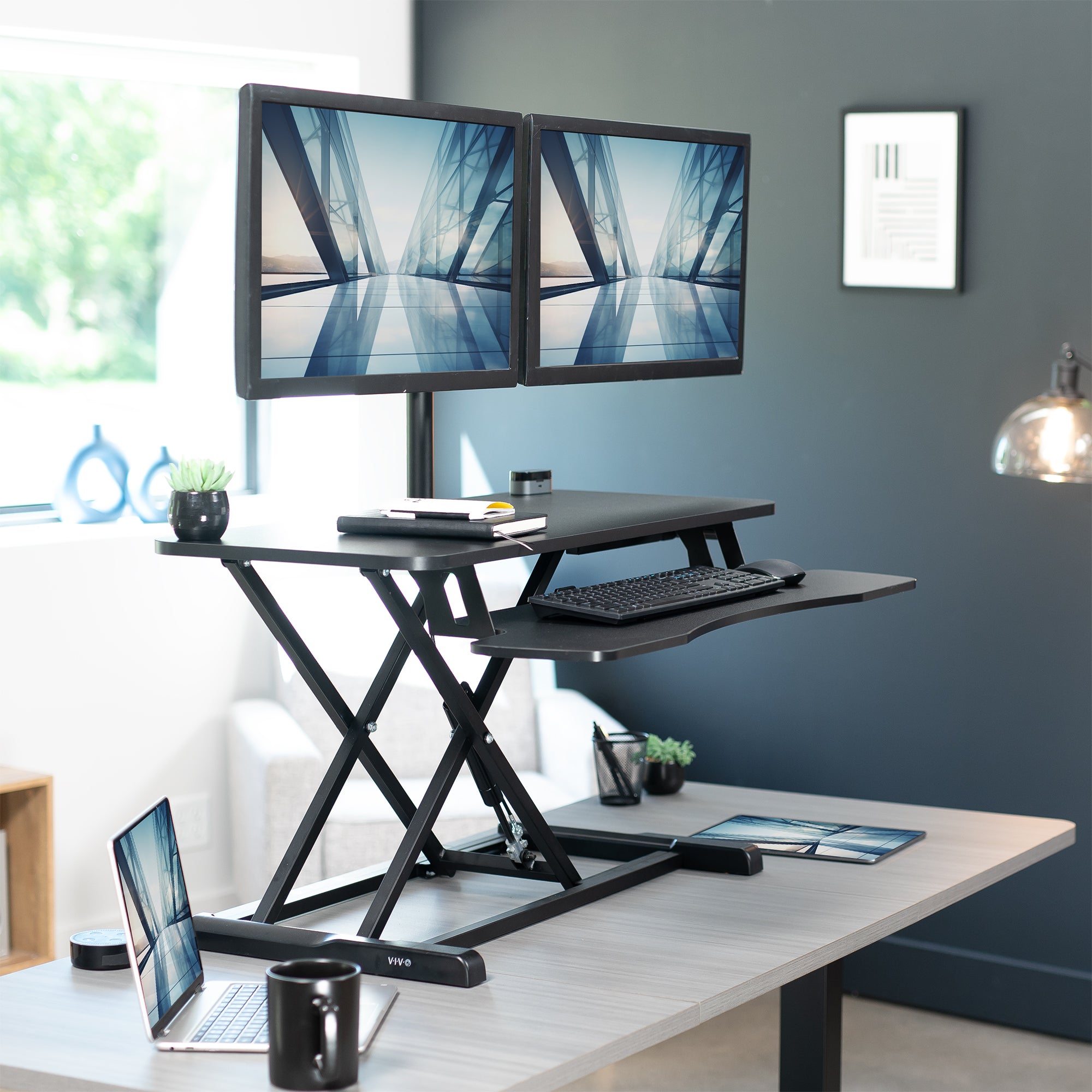 36 inch height adjustable desk riser with articulating pneumatic dual monitor mount.