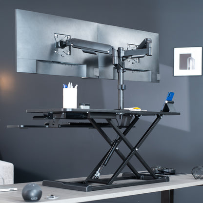 42 inch height adjustable desk riser with articulating mechanical dual monitor mount.