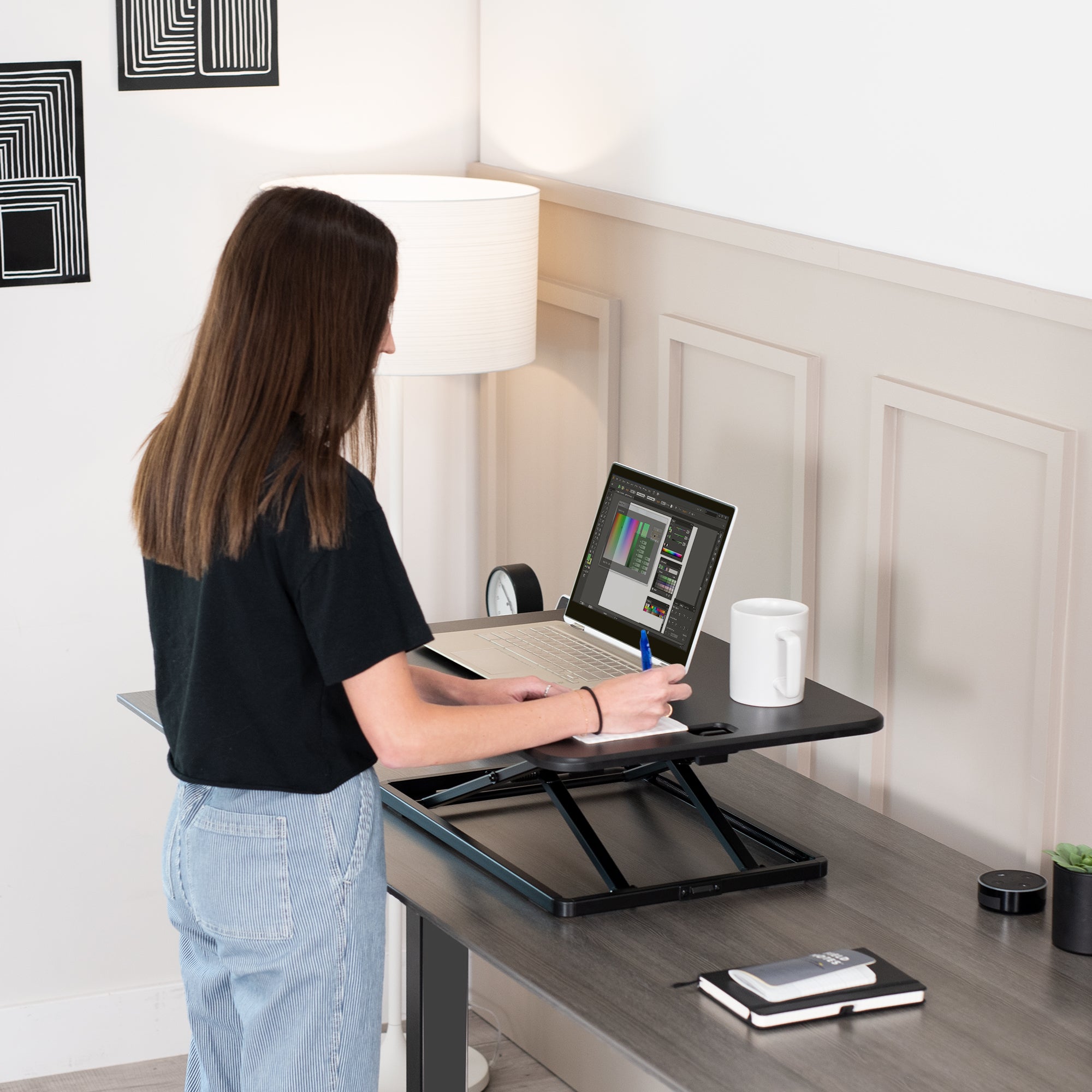 A woman working from a desk with an extended desk riser to work while standing.