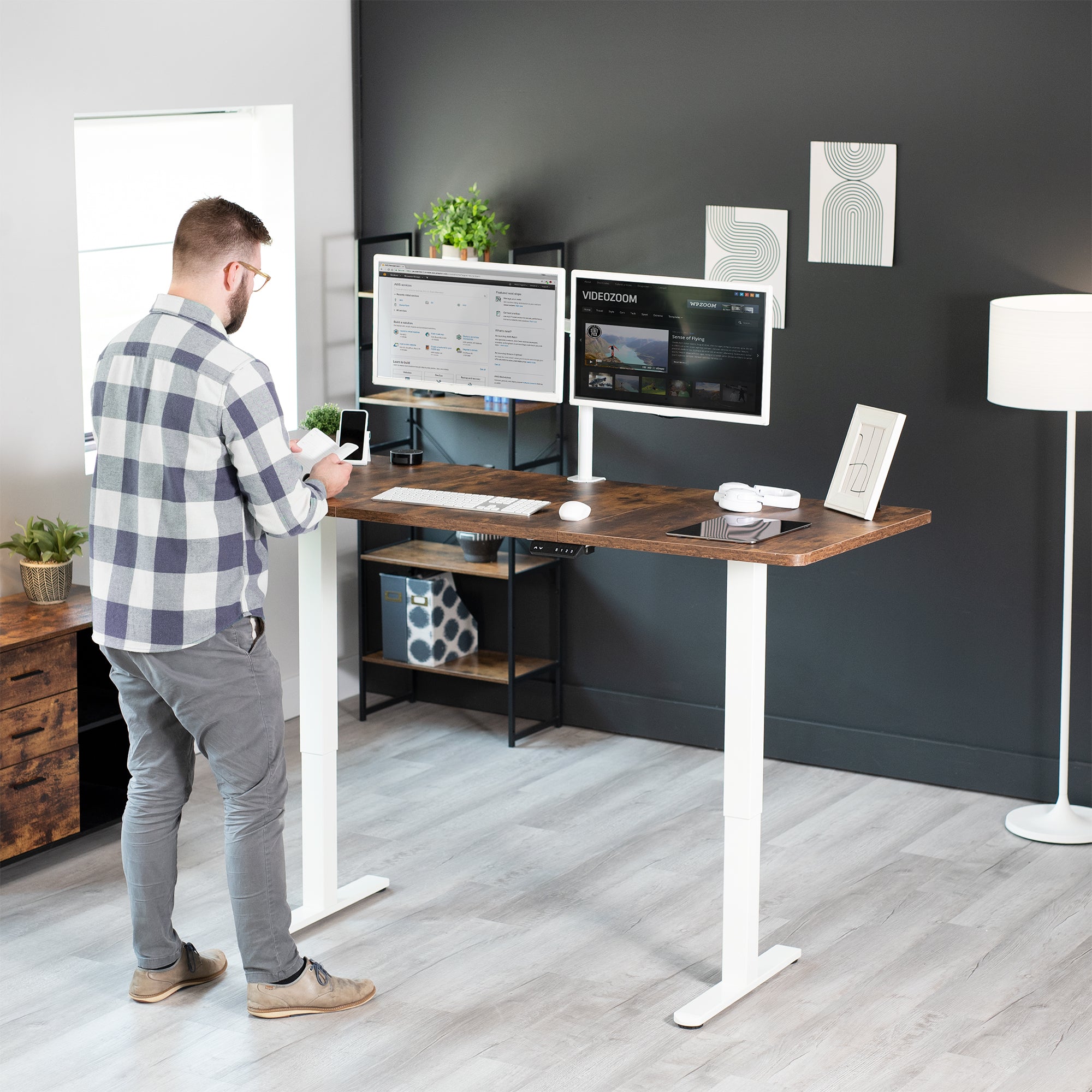 Model standing at electric desk, white frame in home office. 