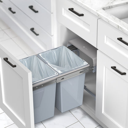 An under-counter dual trash can system with silver containers and a beige lid. 