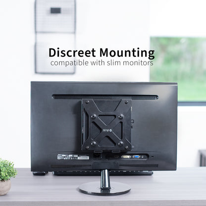 Back view of a monitor with mounting bracket for a Dell OptiPlex Micro on a desk in an office setting