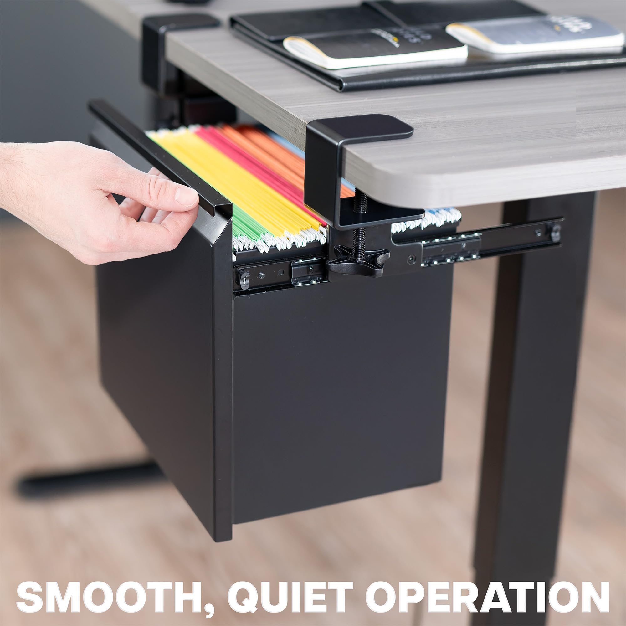 Black file drawer being pulled out from a desk with colorful files inside, on a blurred office background.