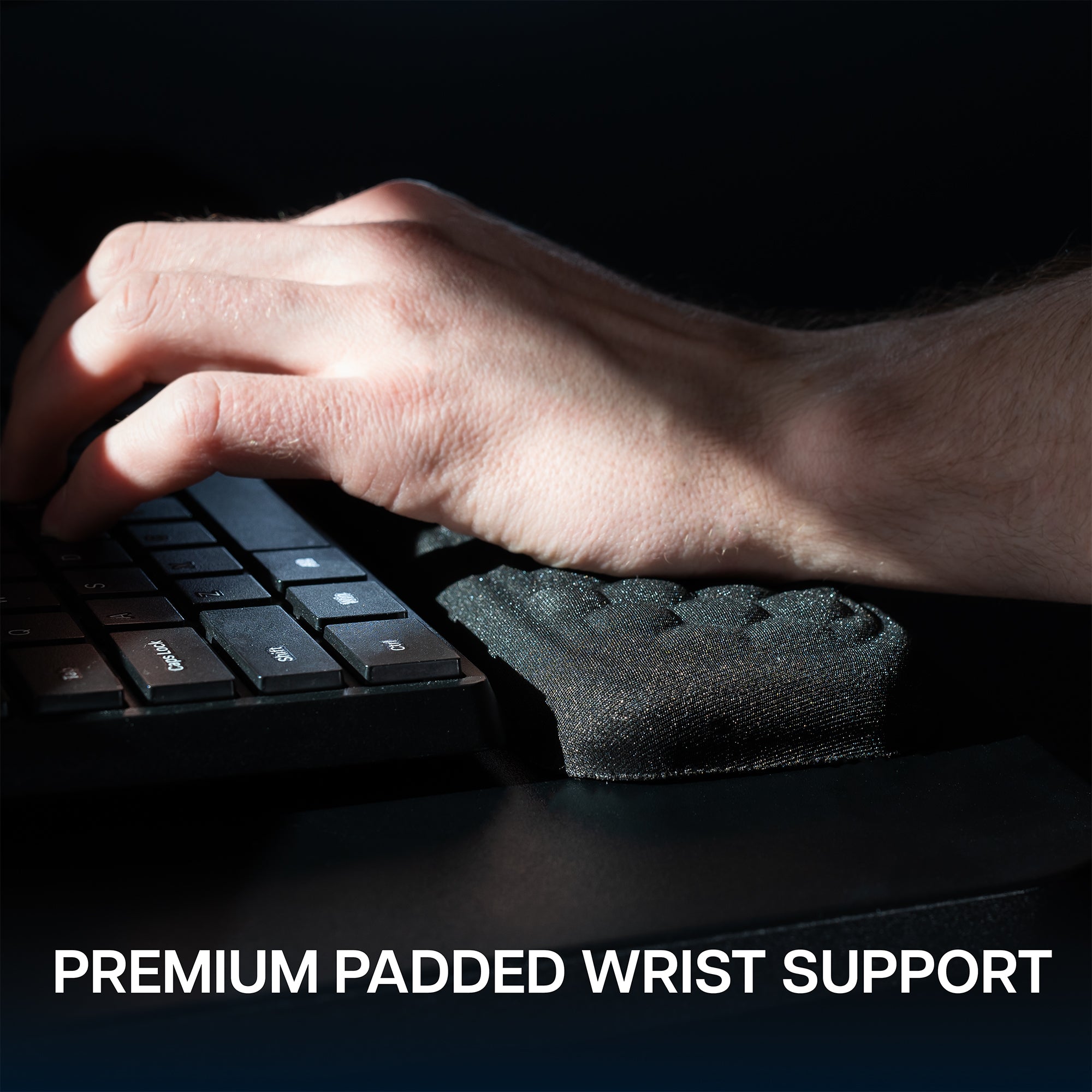 Keyboard tray with a plush wrist pad on a dark background. 