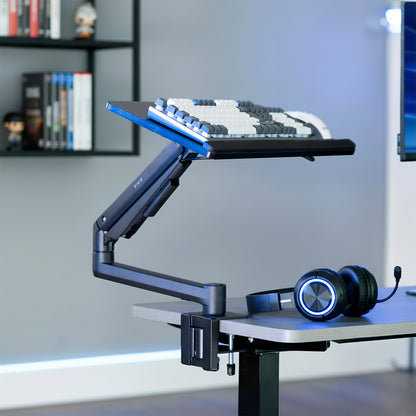 Keyboard on pneumatic mount clamped onto desk in a home office setting.