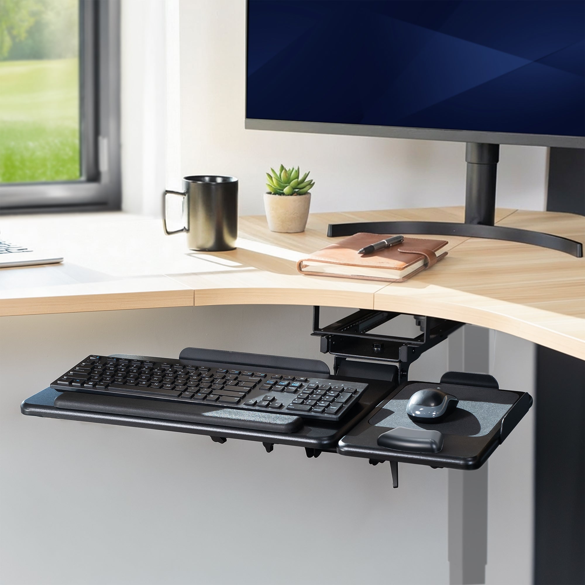 Corner desk setup with a monitor, keyboard, mouse, and office supplies.