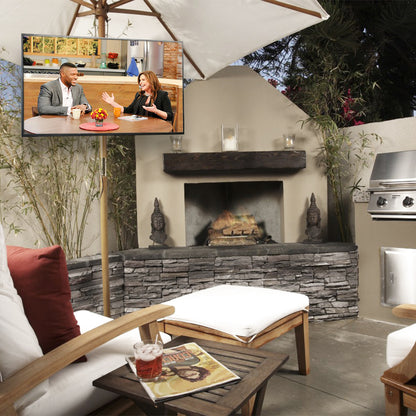 Outdoor living space with a fireplace, patio furniture, and a TV screen displaying two people.