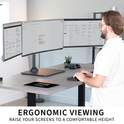 Person using a computer with three monitors at a desk, emphasizing ergonomic viewing.