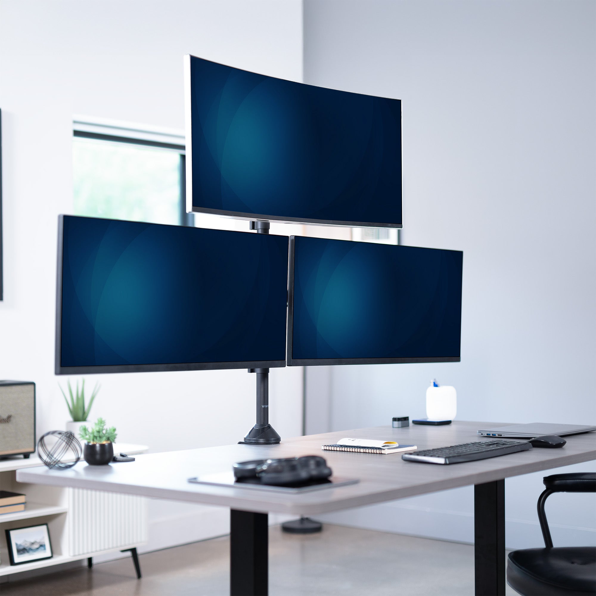 Three monitors on a desk in a modern office setting