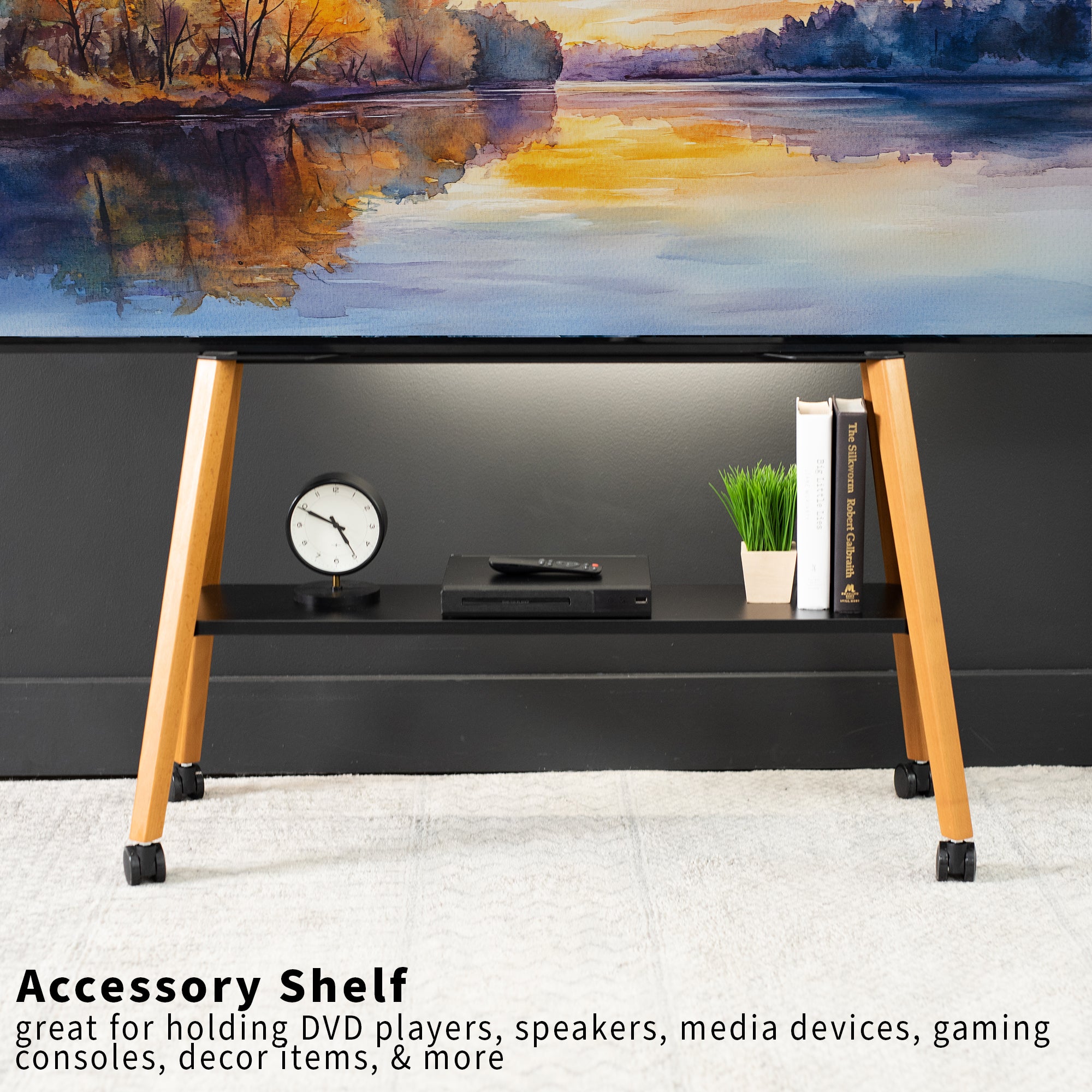 Wooden TV stand with electronic devices against a scenic wall.