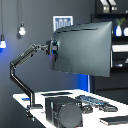 A single ultrawide computer monitor attached to a pneumatic arm desk mount 