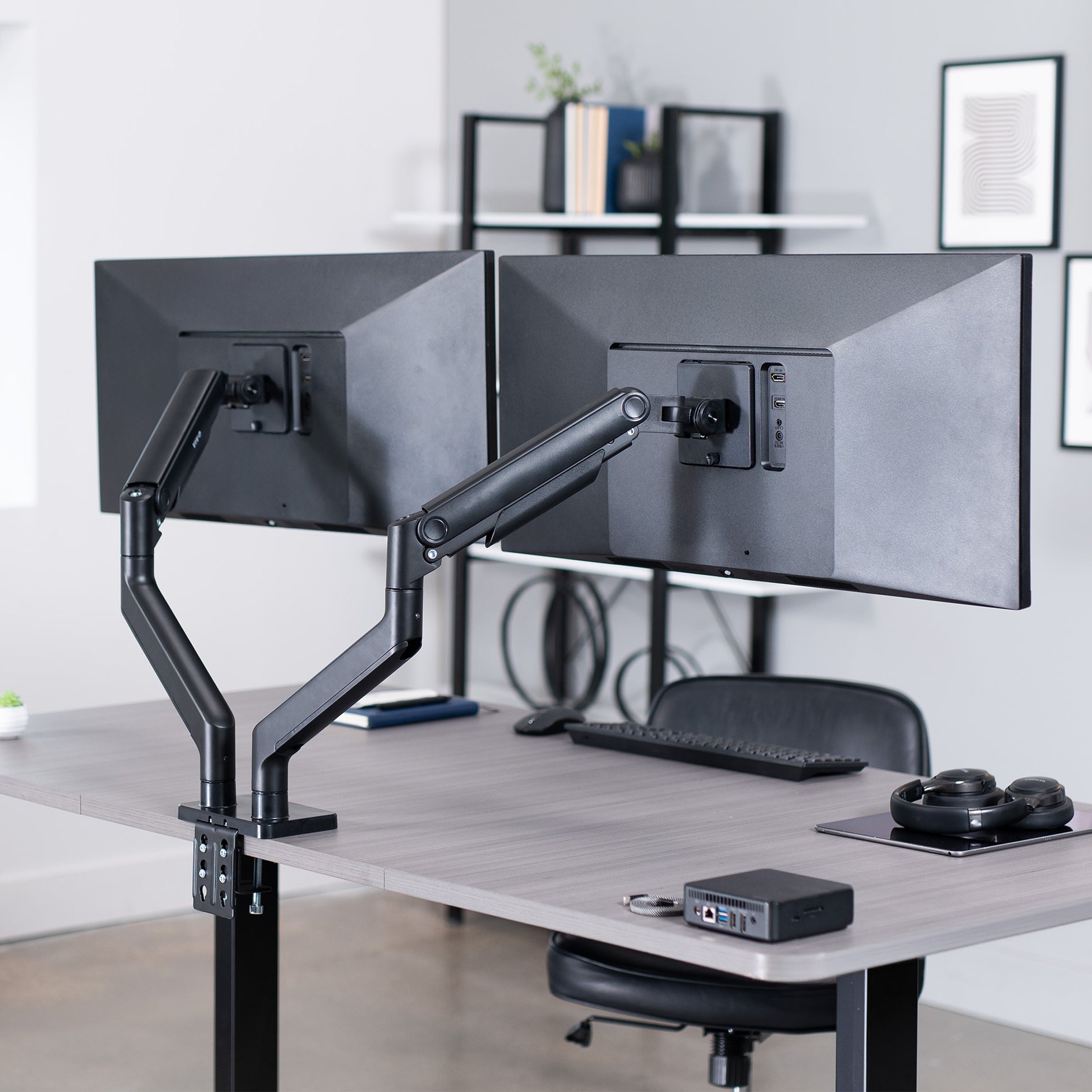 A dual monitor desk mount with pneumatic arms, capable of supporting ultrawide screens.
