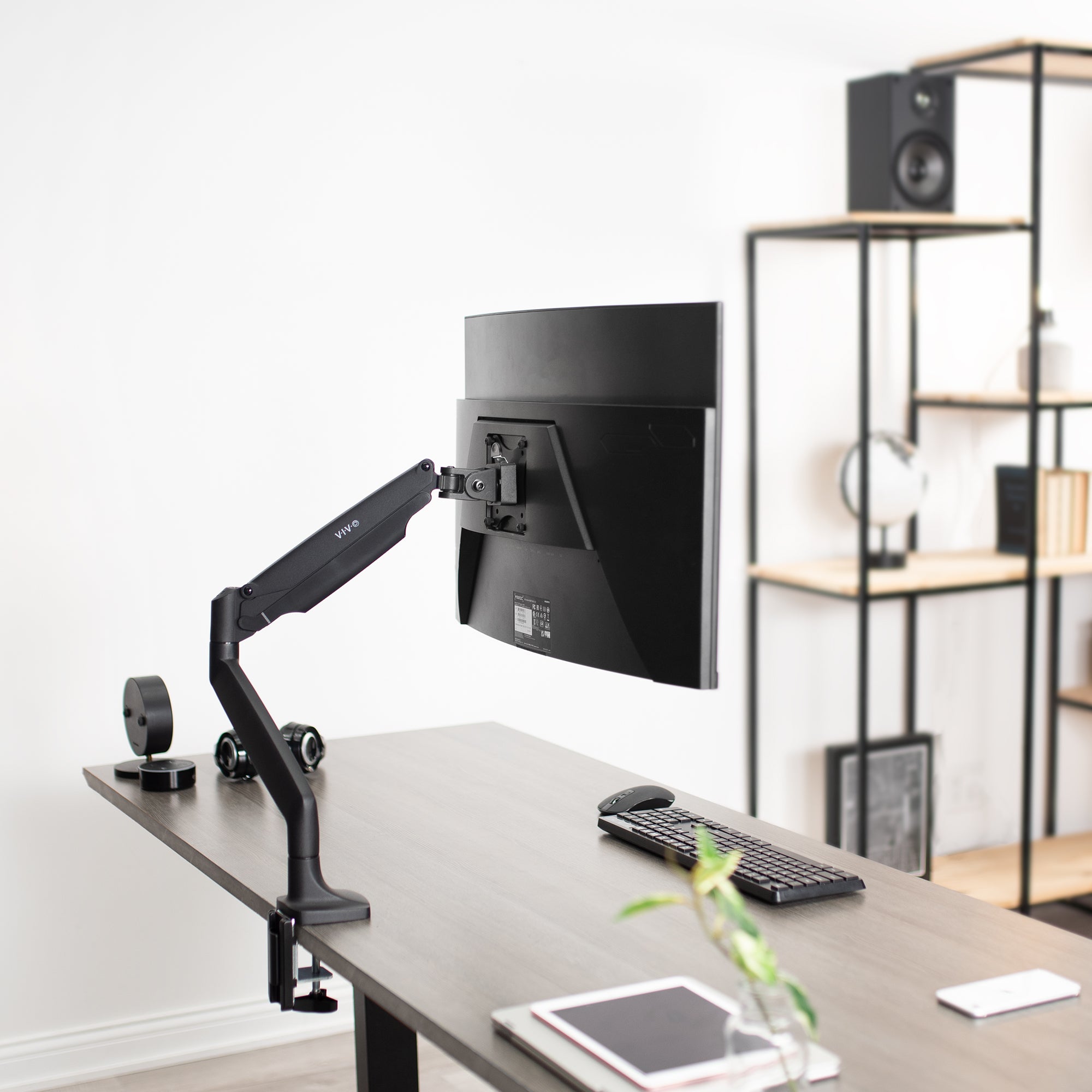 Pneumatic Arm Adjustable Single Monitor Desk Mount mounted to grey electric desk in office setting