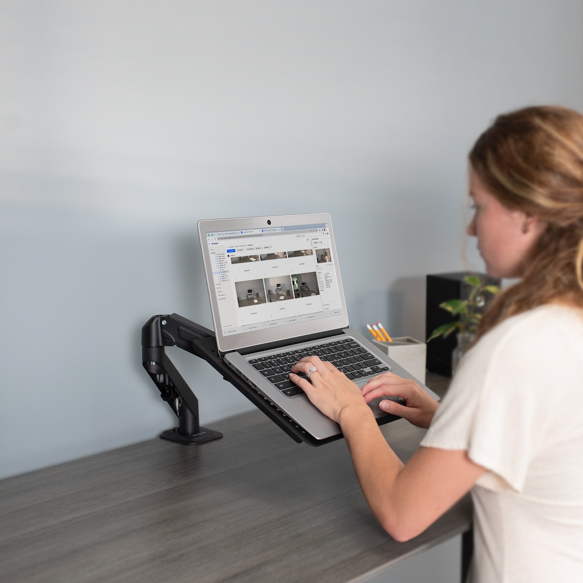 A woman working from a laptop on a laptop tray.