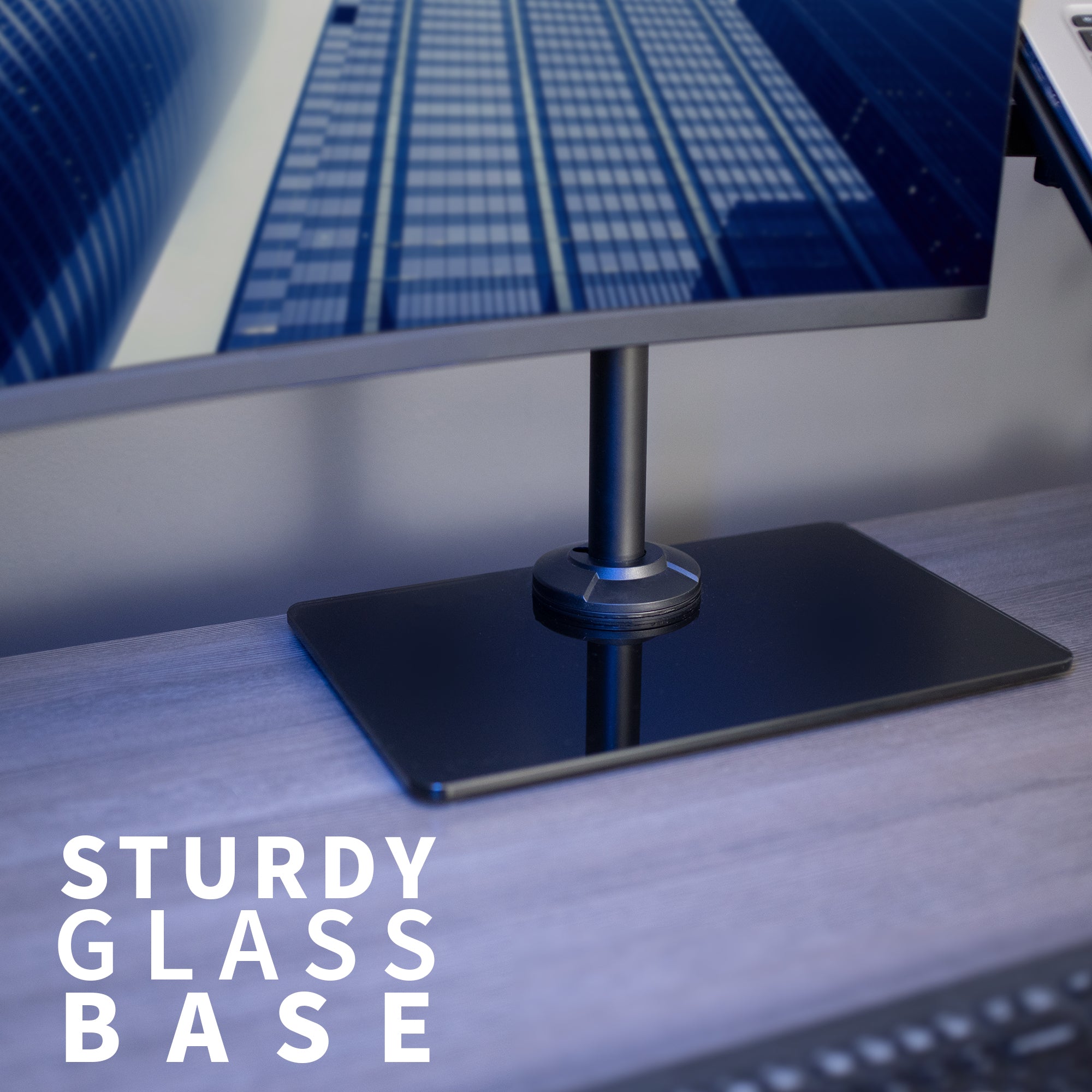 Freestanding monitor and laptop stand with elegant glass base for dual screen viewing and ergonomic placement.